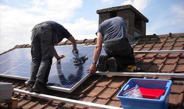 Two workers setting up solar panels in the roof